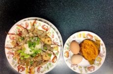 Delicious looking bowl of seafood gumbo with a baked yam and boiled eggs.